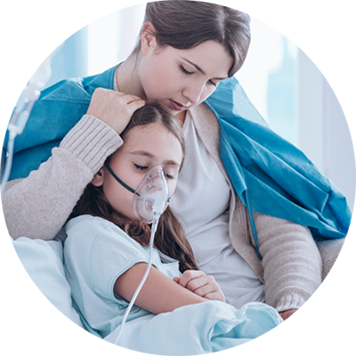 A worried mother holding her daughter who has an oxygen mask over her face.